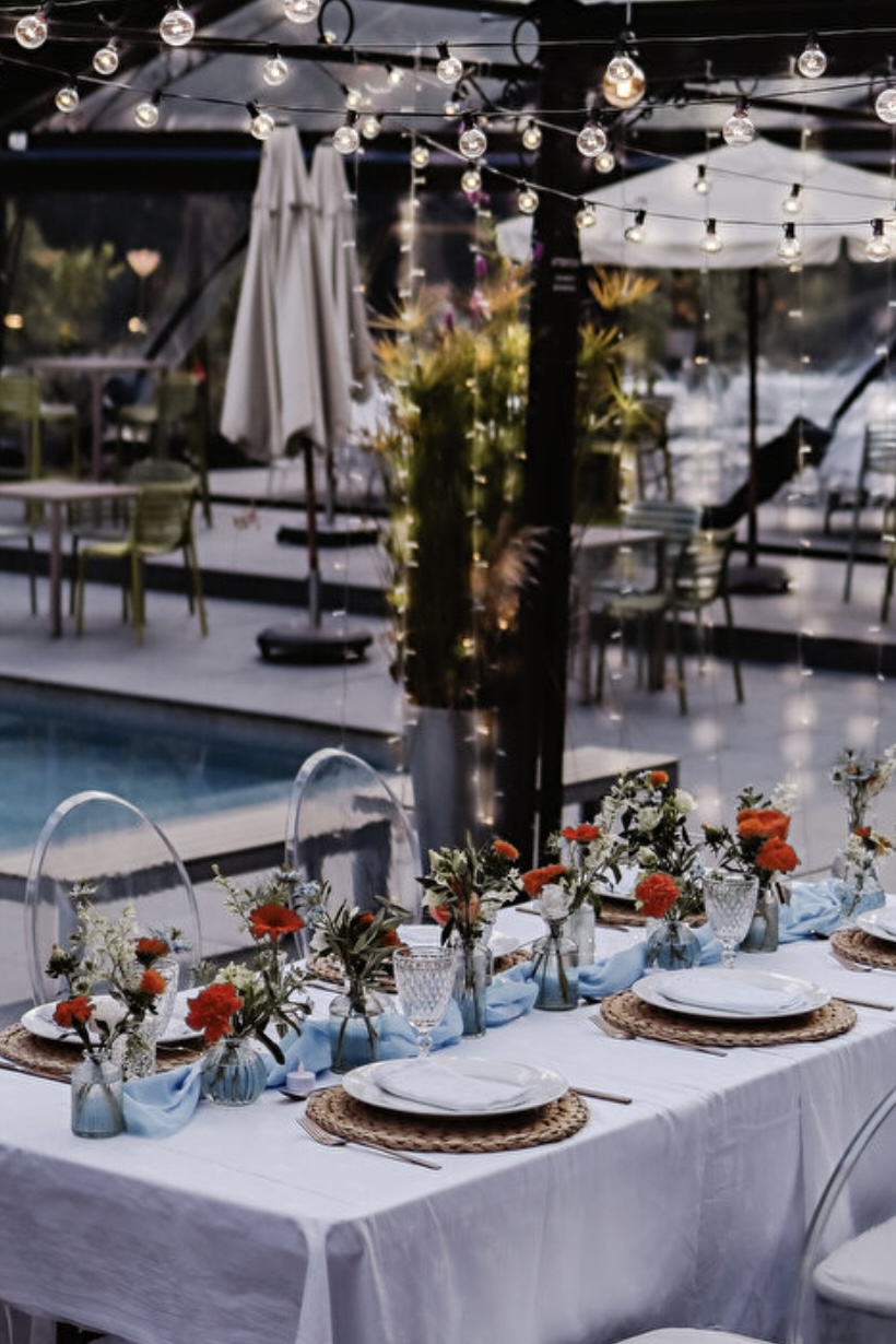 Table blanche avec décoration florale aux abords d'une piscine